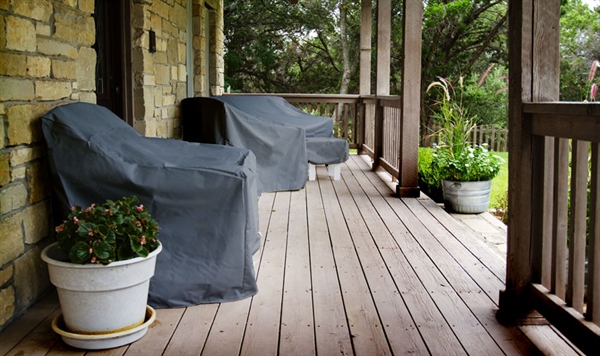 Patio furniture covered with protective covers on a porch, demonstrating how to shield outdoor pool furniture from moisture, debris, and cold temperatures during winter.